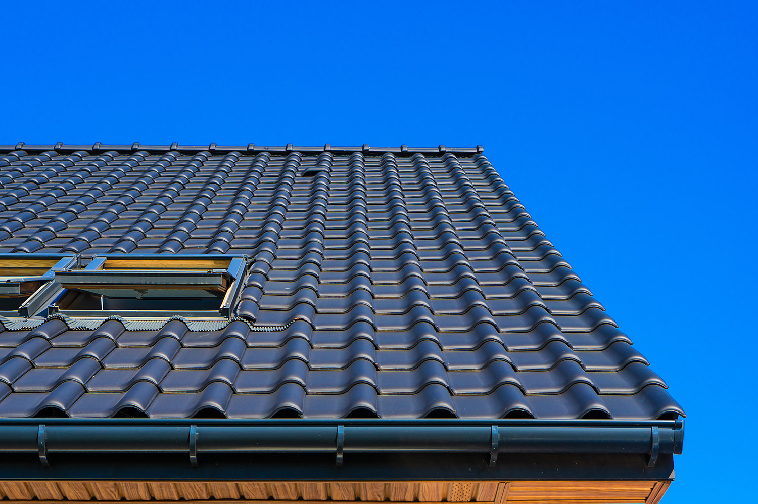 Vertical low angle closeup shot of the black roof of a building with a blue background gaf silver pledge warranty roof